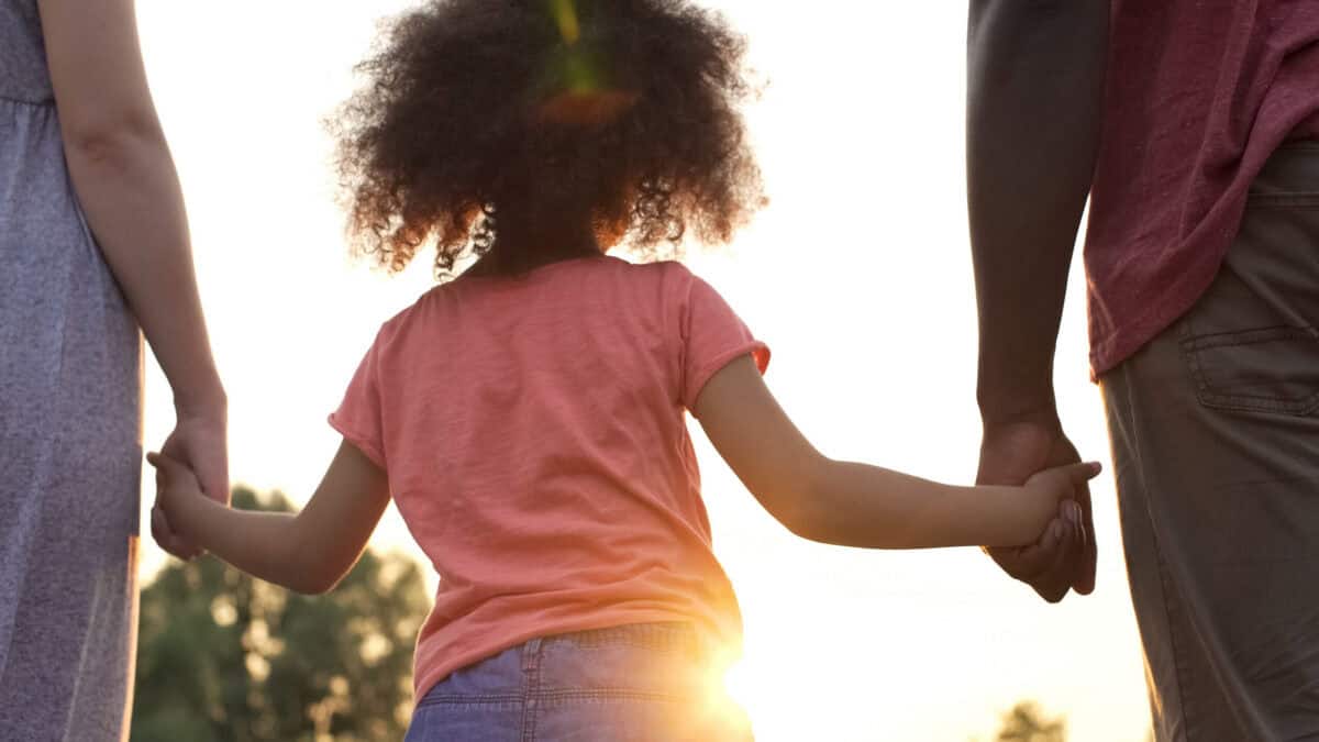 Little girl holds grandfather's and grandmother's hands, happiness
