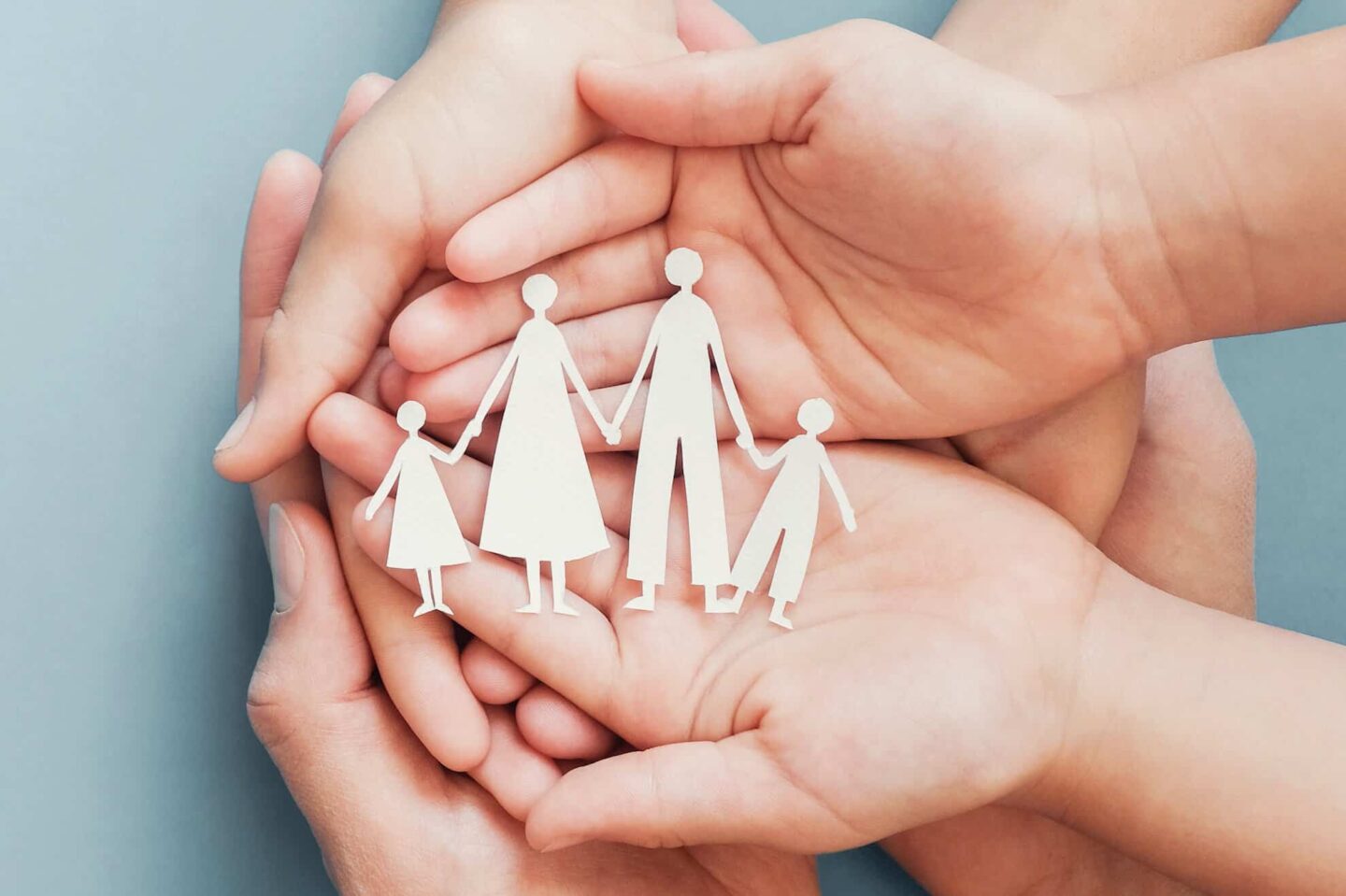 Adult and children hands holding paper family cutout