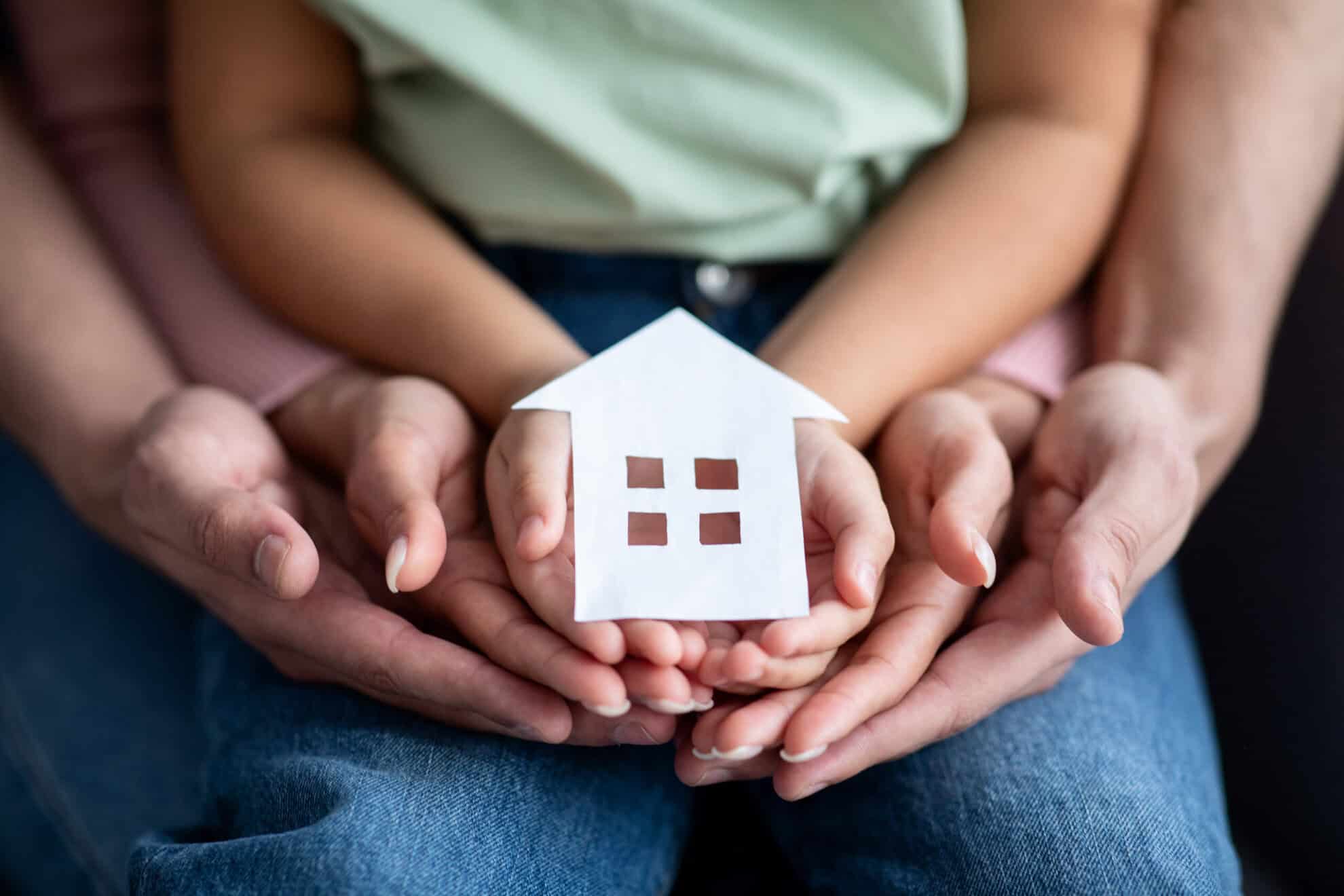 multiple hands holding a cutout of a house