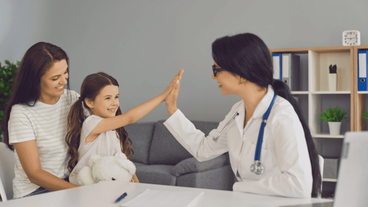 Mother and child in doctor's office. Child is high-fiving doctor.